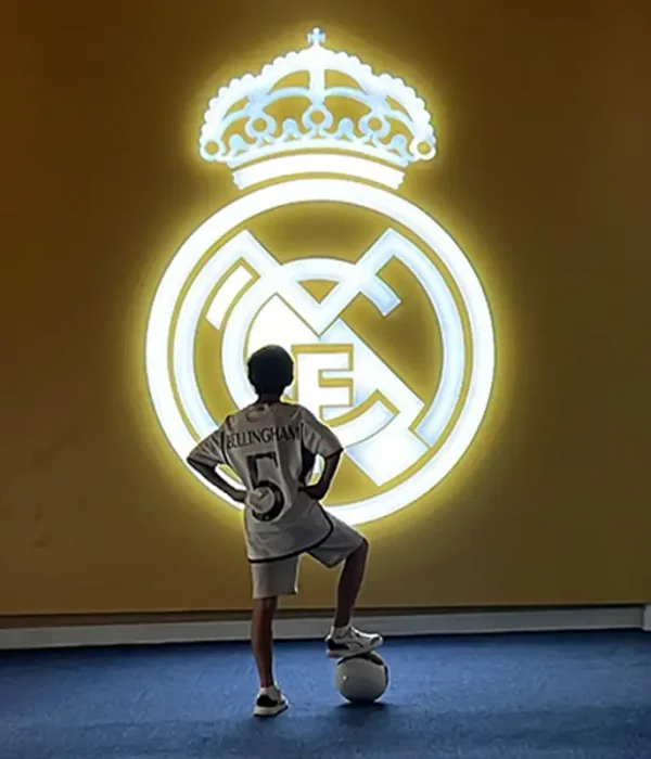 "A panoramic view of Real Madrid Park, featuring lush green spaces, walking paths, and a statue commemorating the club’s legendary history. The park is surrounded by fans and visitors enjoying the scenery and football-related attractions."