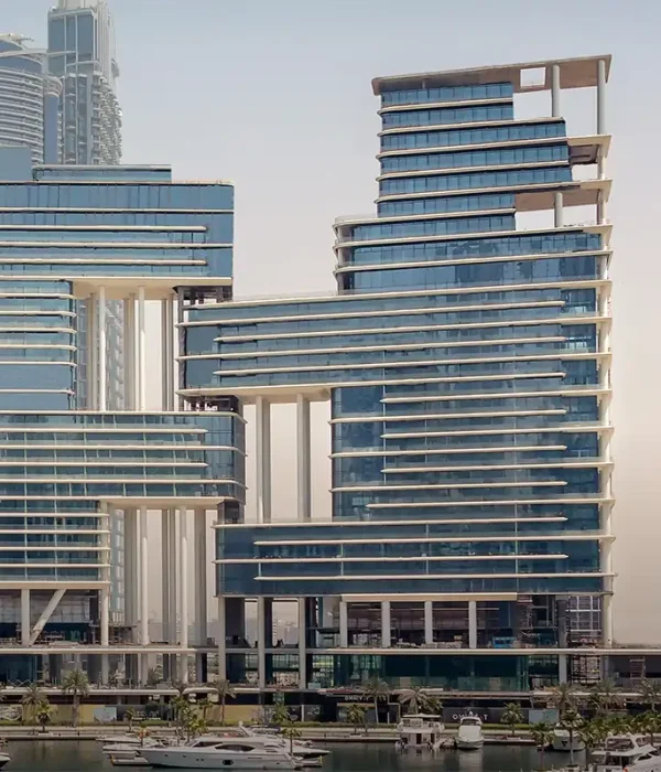 "An exterior view of The Lana hotel, showcasing its modern architectural design with sleek glass panels and towering structure. The surrounding landscape includes lush greenery and a bustling city backdrop, reflecting the luxury and elegance of the hotel."